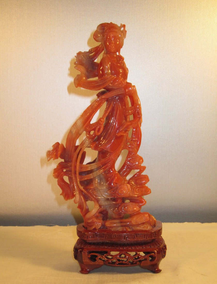 A Tall Chinese Carved Carnelian Figure of Guanyin: circa middle of 20th century, very fine carving, in orange red color with milk white infusion, on fitted stand, good condition; overall 9 in. (23 cm) high, 3.5 in. (8.8 cm) wide 南红ஏ