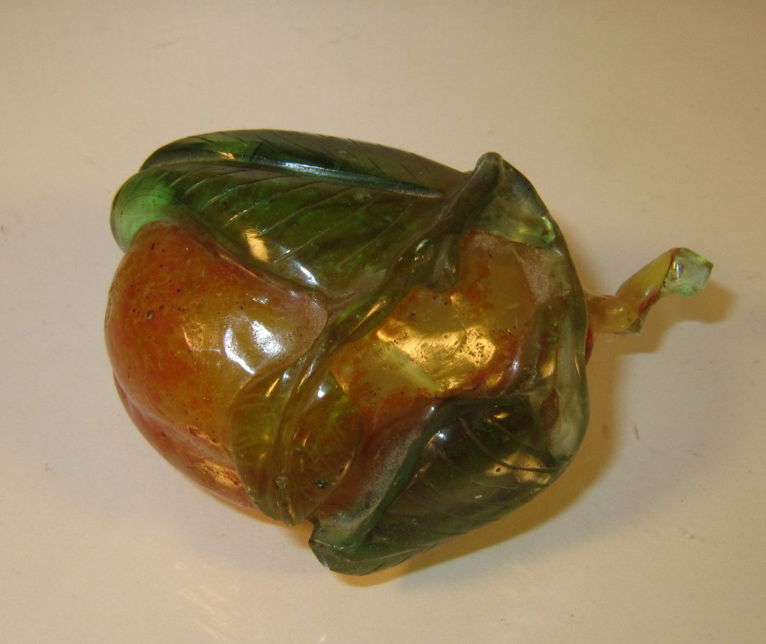 A Chinese Carved Glass Snuff Bottle in Peach Form: circa 19th century, Qing dynasty, well carved green leaves over orange body, two color glass stopper, ivory spoon, stopper stocked to bottle by dried wax, did not try to force open; 2.75 in. (6.8 cm)
