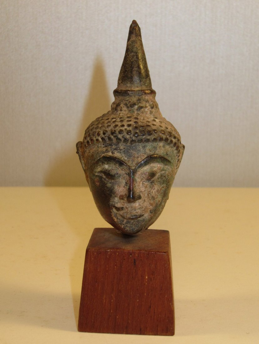 A Small Antique Thai Bronze Buddha Head: circa 12-16th century, originally gilt, good patina, mounted on wood stand, overal 3.5 in. (8.6 cm) high