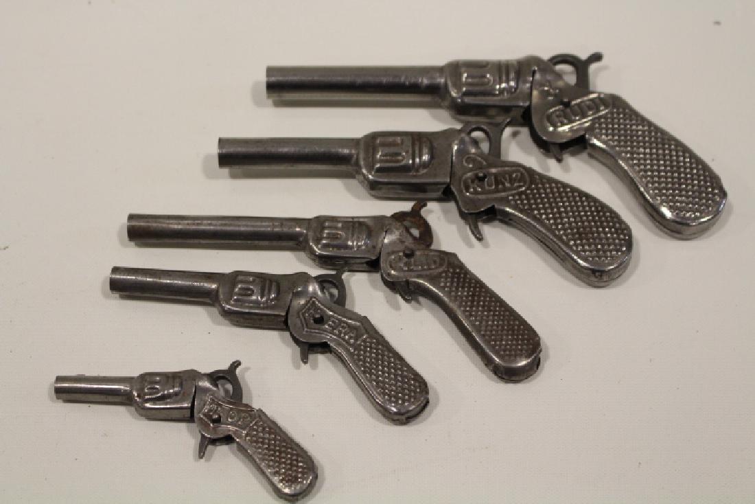 Lot of 5 Tin Toy Cap Guns - Graduated Sizes: Lot of 5 tin toy cap guns, fires single cap, squeeze trigger, each marked DRP, graduated sizes - smallest 3 1/4" marked Top; Hera; Kunz; Klio; largest Rudi. All triggers work