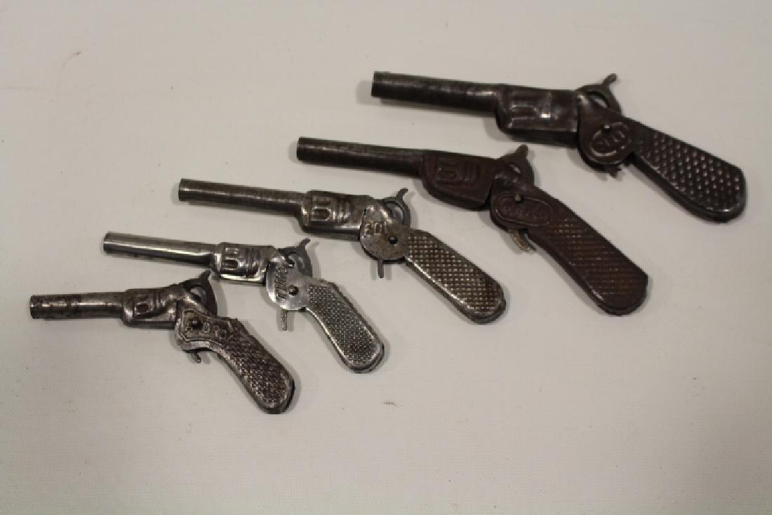 Lot of 5 Tin Toy Cap Guns - Graduated Sizes: Lot of 5 tin toy cap guns, fires single cap, squeeze trigger, 3 marked DRP, graduated sizes - smallest 4 1/4" marked Adro; Timo; Edi; Hero; largest Celt. All triggers work.