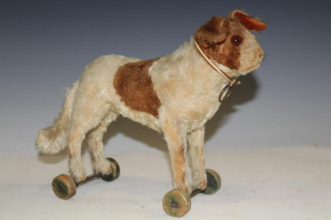 Steiff Stuffed Dog Pull Toy: 1920-30s Steiff stuffed dog pull toy, wooden wheels, spotted mohair "fur", glass eyes, 8 1/2" H, 9" L plus tail, lacking original button.