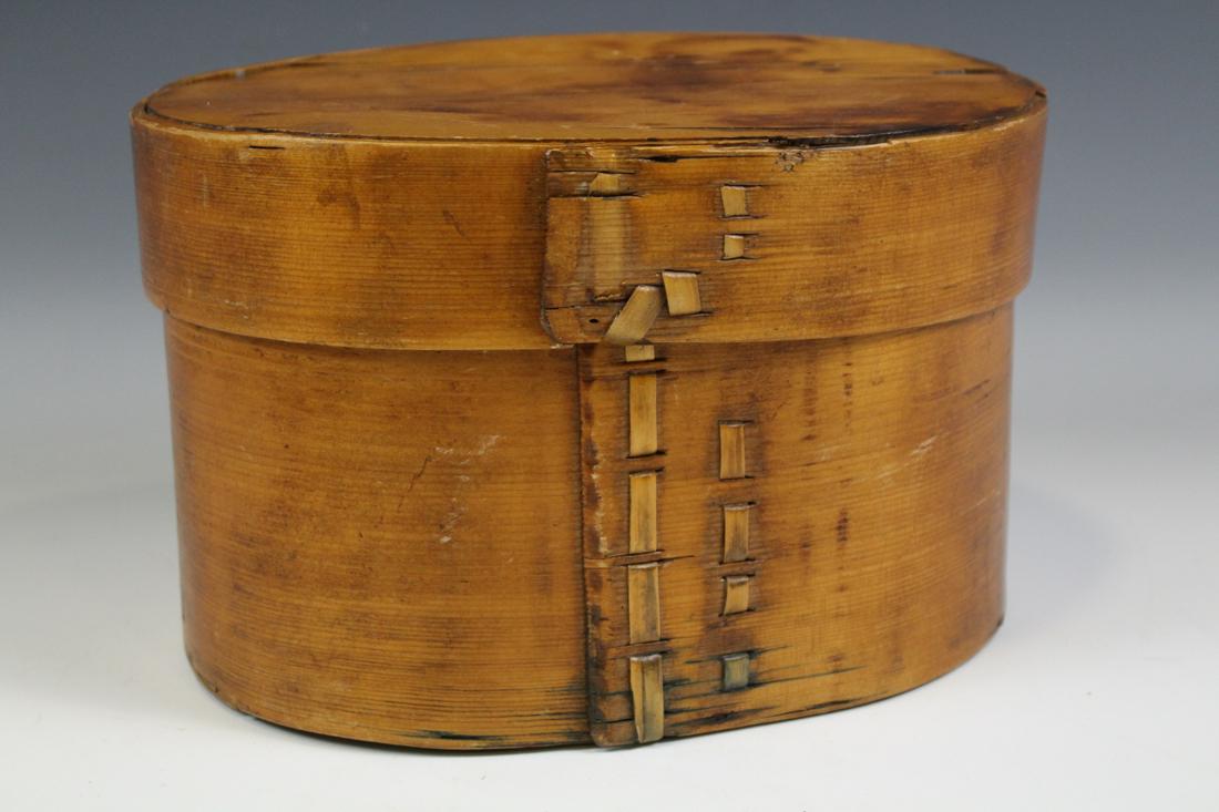 Oval Laced Laps Pantry Box: 19th century oak oval panty box, unusual lace secured laps on lid and base, 7" H x 10" W. As with many other lots in this auction, this lot has museum catalog numbers hand-printed discreetly in small 