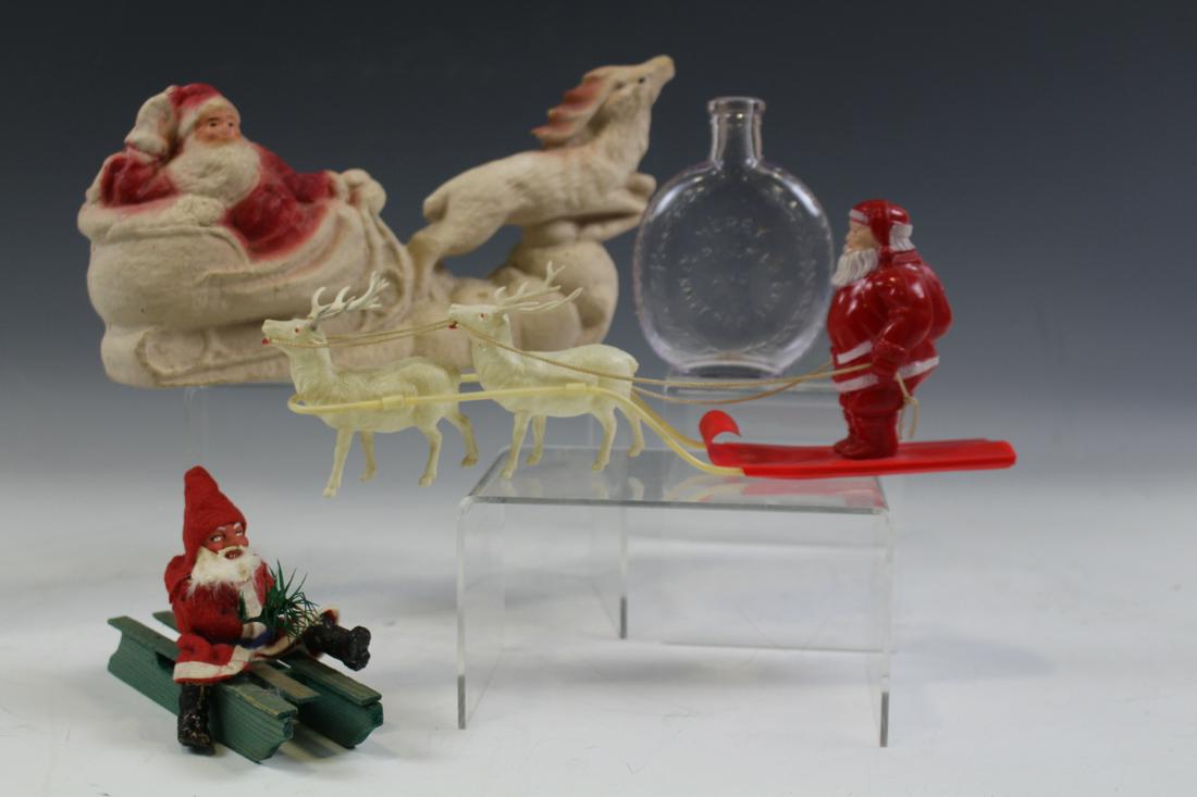 Santa Claus Figures & Christmas Flask: Lot of 4 Christmas holiday items - molded cardboard Santa and sleigh 11" L; celluloid stand-up Santa & reindeer; felt Santa on sled; Merry Christmas and Happy New Year flask, 4 3/4 H.