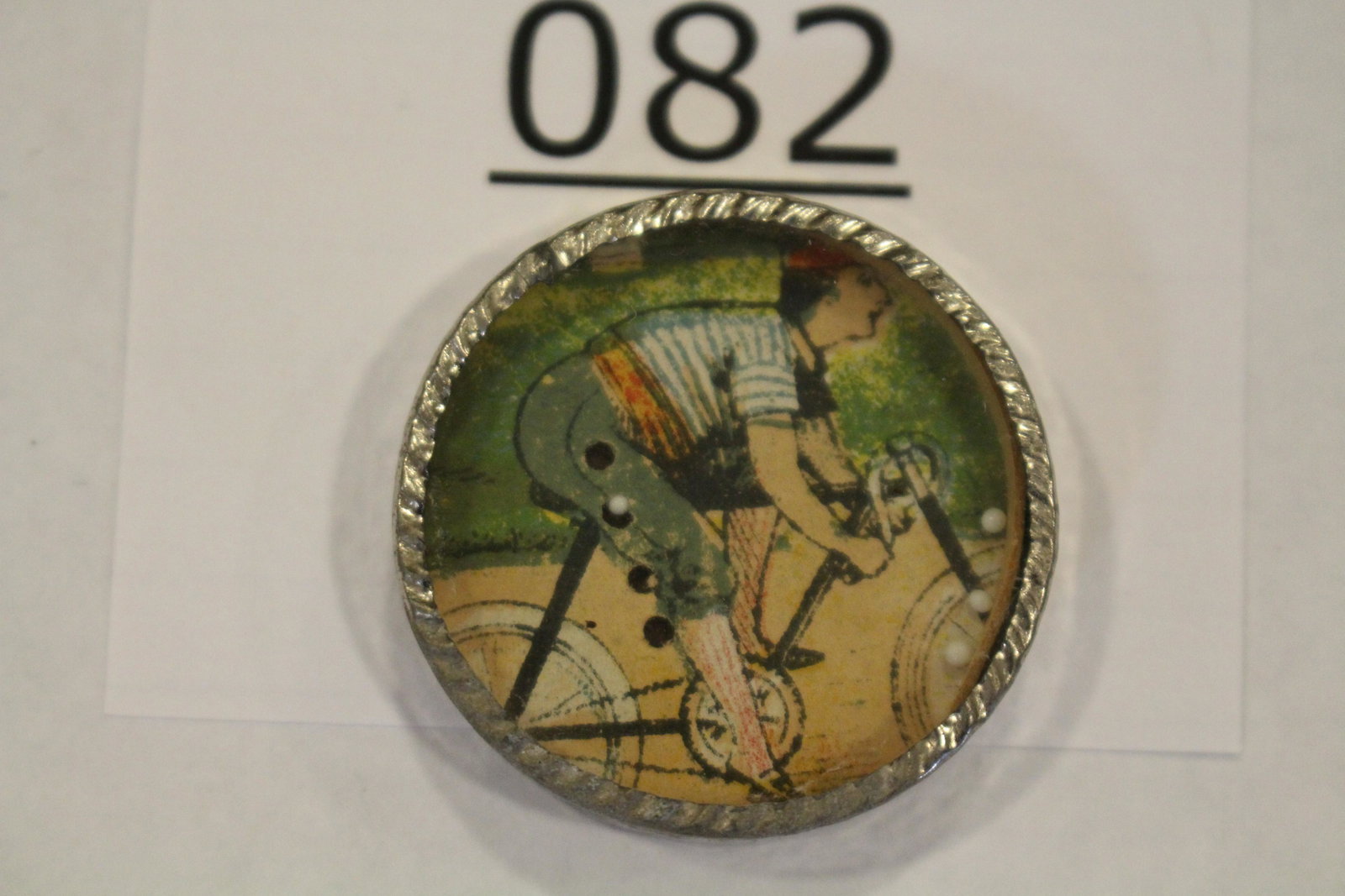 Boy Riding Bike Dexterity Game: Dexterity game / handheld puzzle game with image of a boy wearing knickers and riding a bike, metal frame, mirrored back, 1 1/2" W. Good.