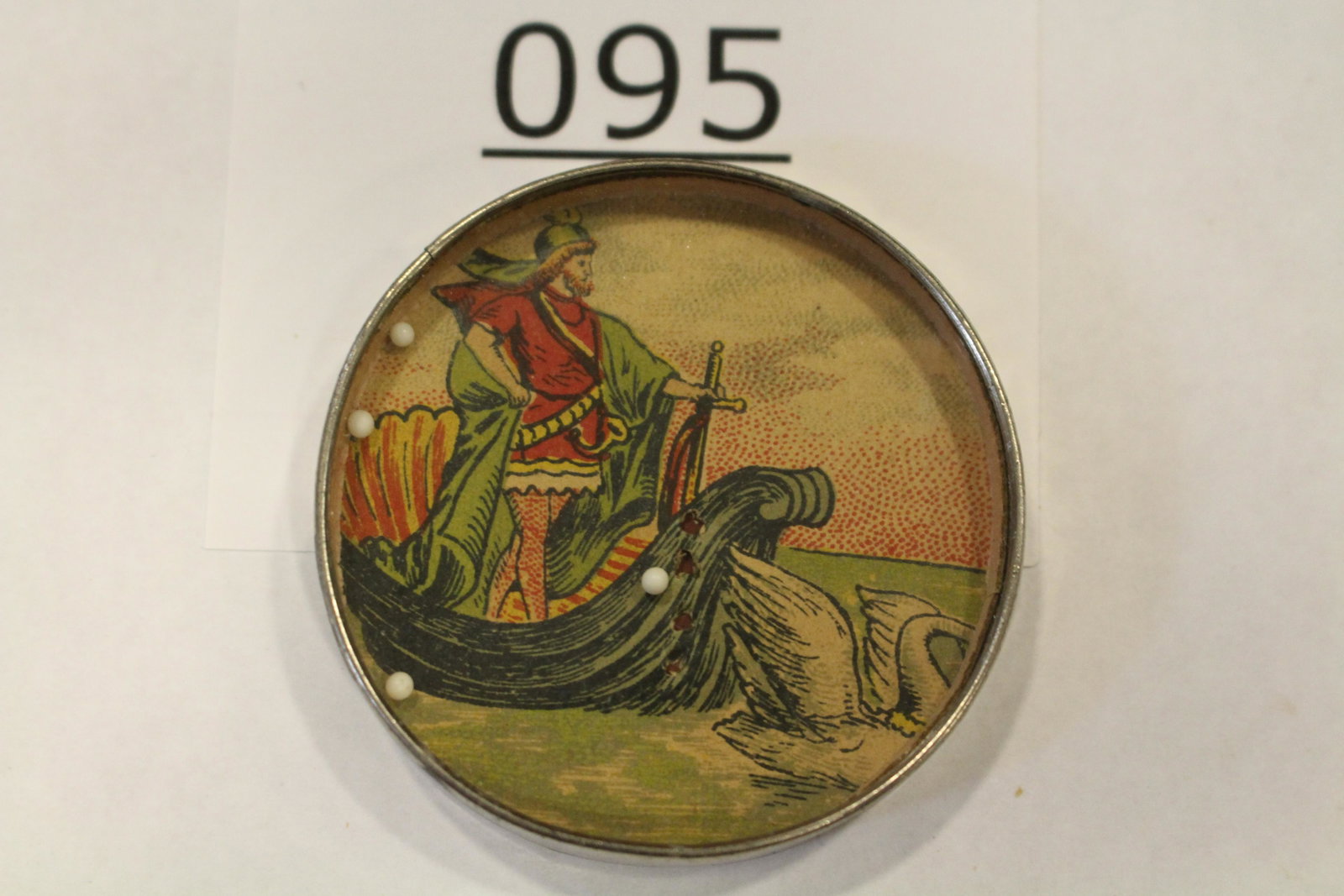 Viking Soldier / Guard Dexterity Game: Dexterity game / handheld puzzle game with image of a Nordic / Viking soldier in full garb riding in his boat with sword in hand, swan in foreground, metal frame, mirrored back, 2" W. Good.