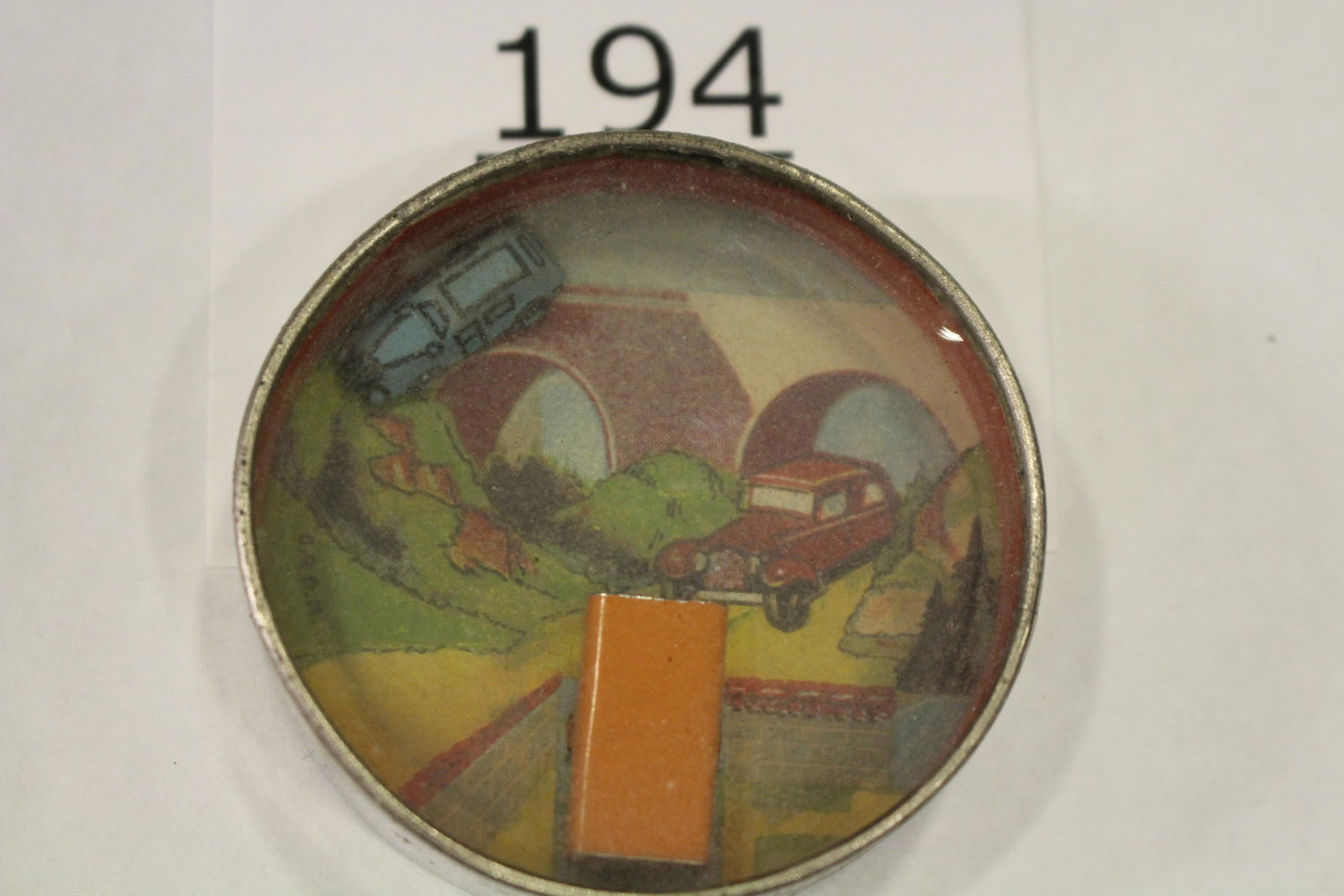 1930s Automobile Dexterity Game: Dexterity game / handheld puzzle game with image of a painted metal car with background of a country road, challenge is to put the auto into the metal building, metal frame, cardboard back, 2 1/4" W.