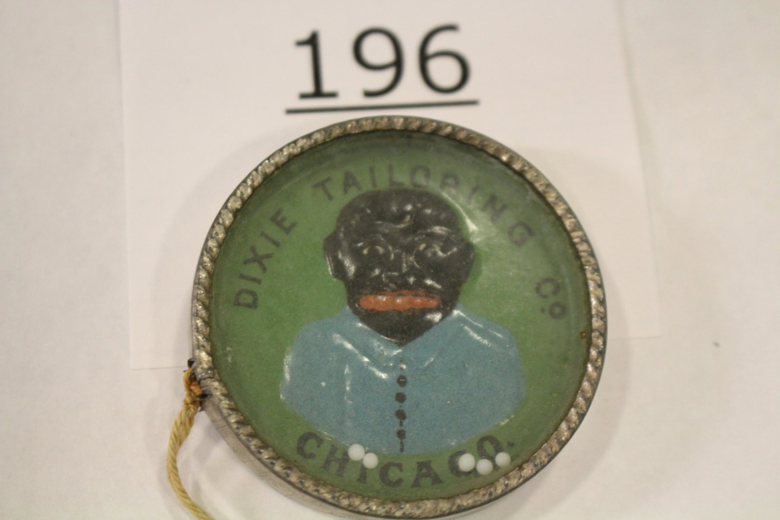 Advertising Dixie Tailor Co. Chicago Dexterity Game: Dexterity game / handheld puzzle game with embossed image of a black man's portrait, front labeled "Dixie Tailoring Co., Chicago" metal frame, cardboard back, 1 3/4" W. Good.