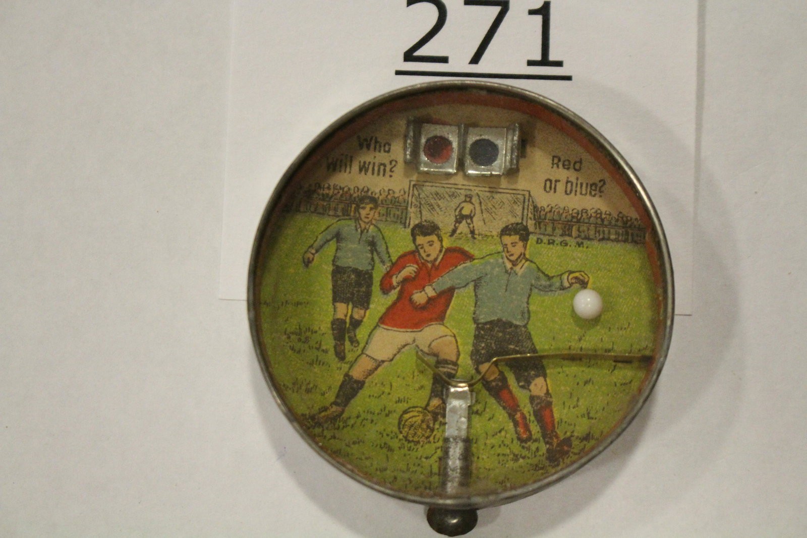 Sports-Themed Soccer w/ Metal Plunger: Dexterity game / handheld puzzle game with image of soccer players, front labeled "WHO WILL WIN? RED OR BLUE" with metal spring action plunger, accessible from outer rim, challenge shoot ball towards