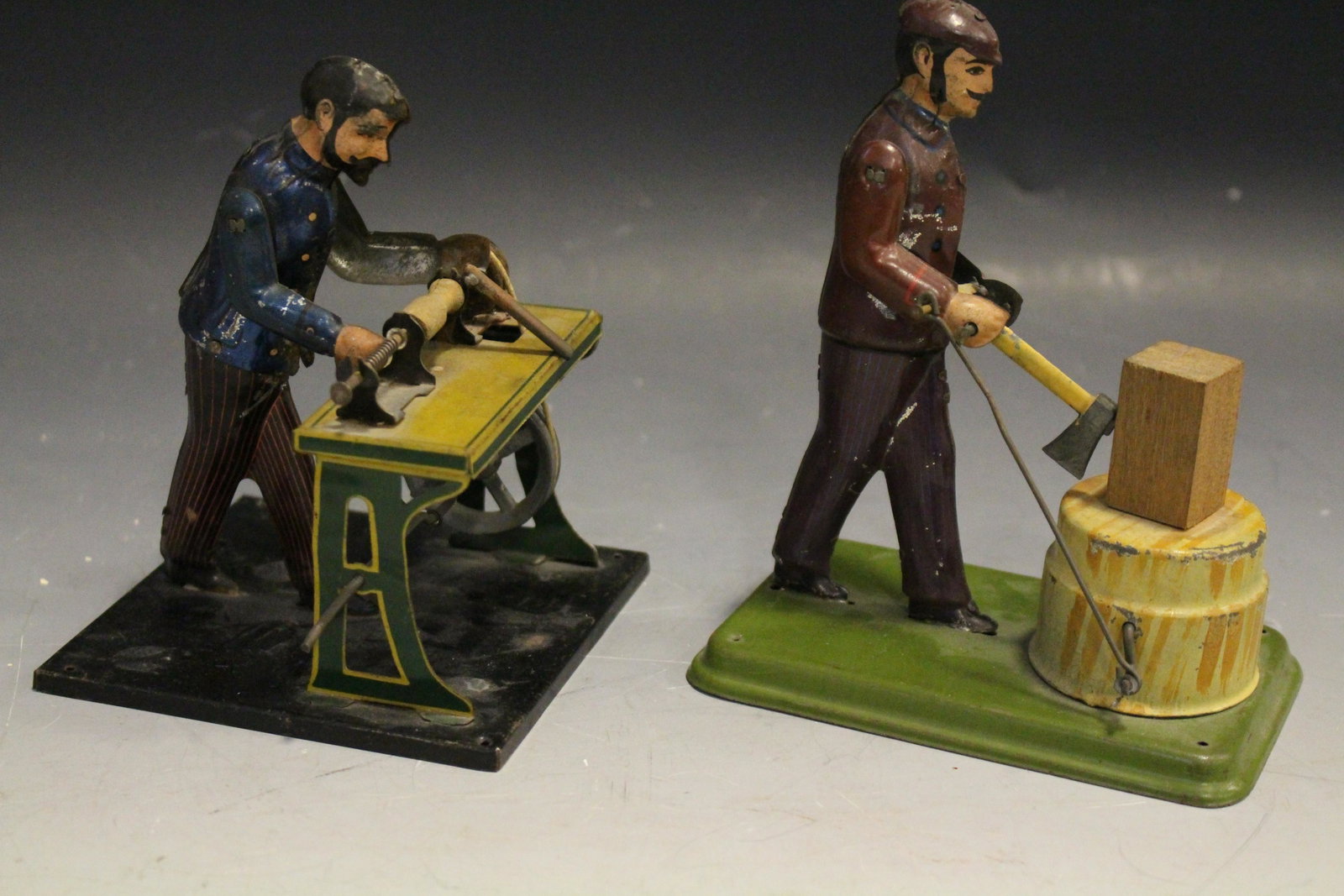 Tin Lithographed Carette Steam Toy Accessories: Lot of 2 Tin Clarett Lithographed Steam Toy Factory Worker Accessories, each about 5 1/4'' H - 1) man at wood lathe; 2) man chopping wood with axe. Both work when cranks are turned.