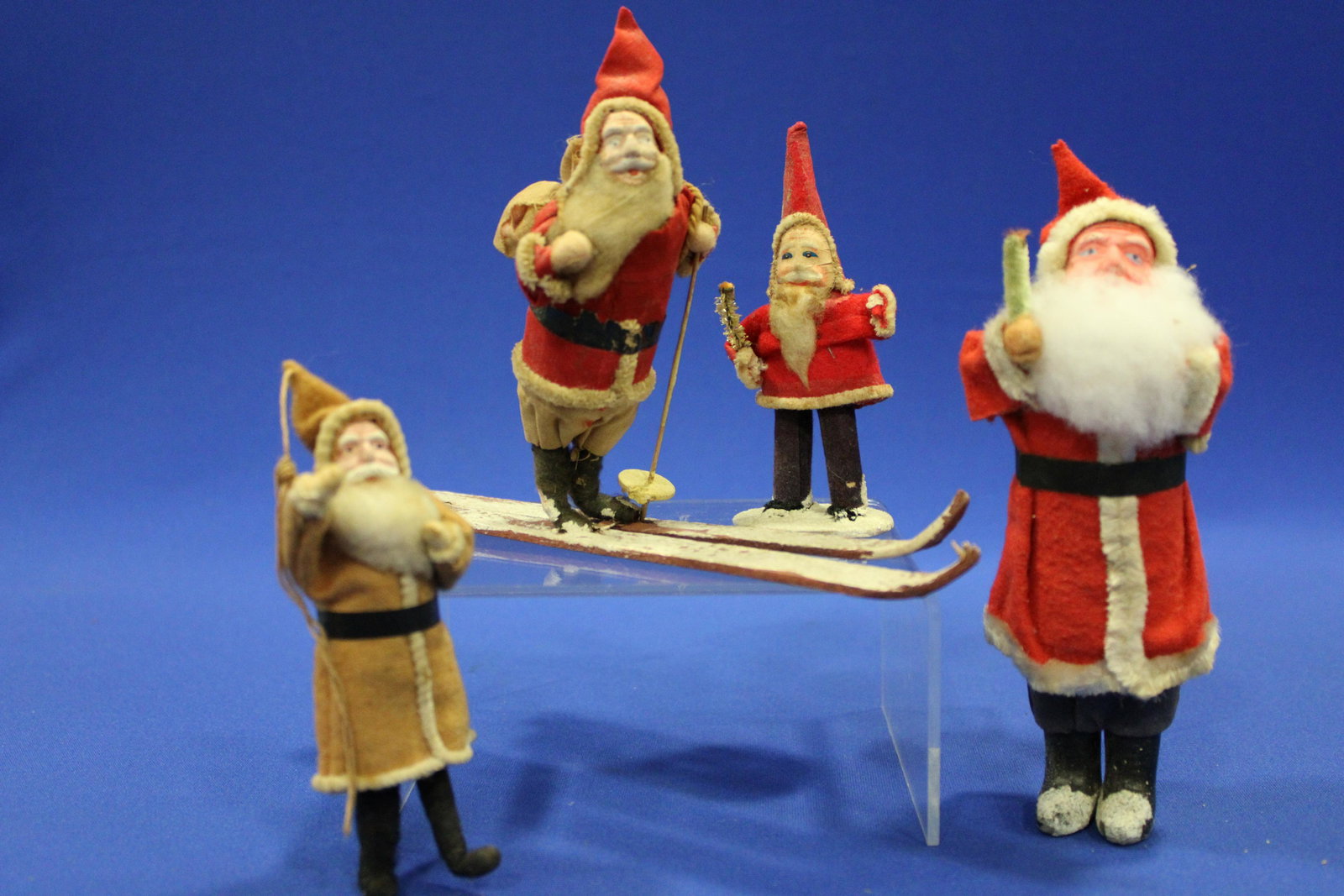 Antique Santa Claus - Figures Felt Suits & Bisque Faces: Antique Group of Santa Claus Figures in Felt Suits with Bisque Faces - 1) Santa in silk-like suit on skis with back pack, lacking one pole, 5 1/2" H; 2) Santa in fabric suit, cotton beard holding pipe