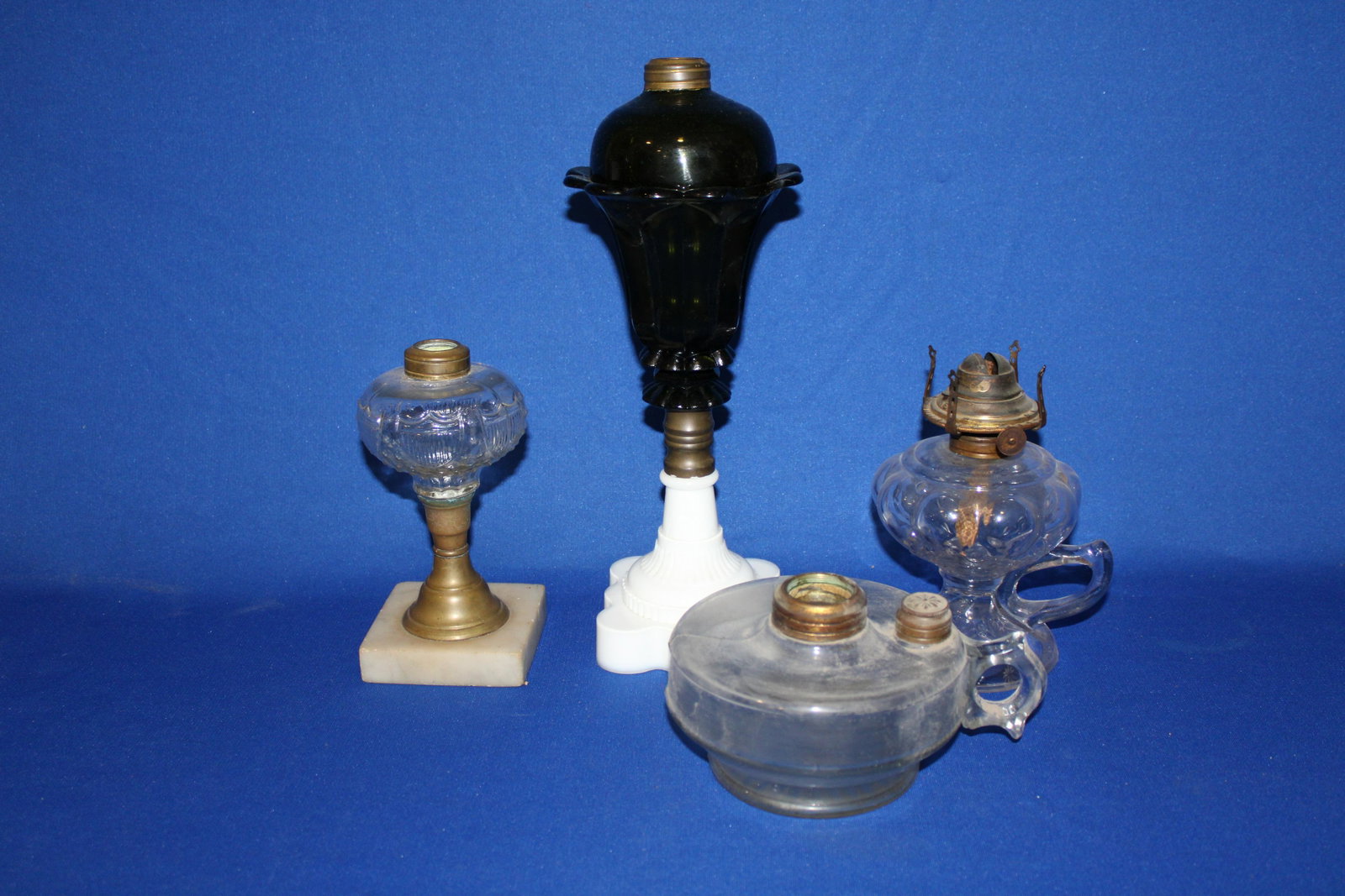 19th C Glass Oil Stand & Hand Lamps: 19th C Glass Oil Lamps - 1) Federal shield; bracket finger lamp; finger / hand lamp; tall purple lamp with white base, chips to ruffled rim.