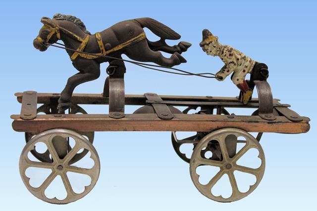 Watrous Clown & Pony Bell Toy: Watrous clown and pony bell toy, painted cast iron and steel, front axle turns and make pony gallop and clown moves back and forth, heart designed metal wheels, 10" L.