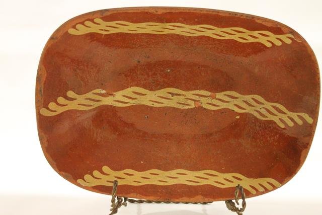 Redware Pennsylvania Loaf Dish: Early 1800s redware oblong loaf dish, coggle edging, Pennsylvania, interior with three honeycomb bands of yellow slip decoration, shiny, clear lead-glazed surface, 14" L x 9 3/4" W x 2 3/4" H.