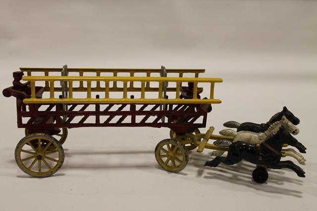 Kenton Fire Ladder Wagon 3-Horse Team: 1930-50s Cast iron Kenton ladder fire truck, 2 seated firemen, yellow ladders and running gear, pulled by 3-horse team of two black and one white horse, red open frame wagon, yellow spoke wheels. 16''