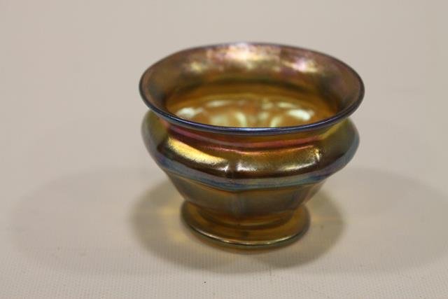 Tiffany Favrile Master Salt Dip Art Glass: Gold iridescent with contrasts of violet-red, footed pedestal base, signed in script "Favrile L.C.T.", 2 1/4" W x 1 1/2" H.