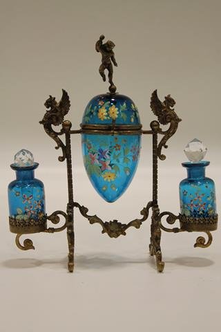 Griffin & Cupid Moser Enameled Dresser Set: Rare, holder decorated with cupid, two winged griffins, and lion head, fitted blue glass with multi-colored enameling, top has lidded jar in egg form, bottom holds two fitted perfumes, 6" H.