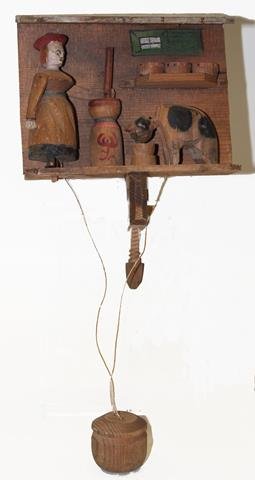 Folk Art Nodders - Cow and Milkmaid: Wooden carved mechanical homestead scene, tug on pendulum and cat laps from bucket and milk maid's arm goes up and down churning butter, hand-painted, wooden clamp, 6 1/2" W.
