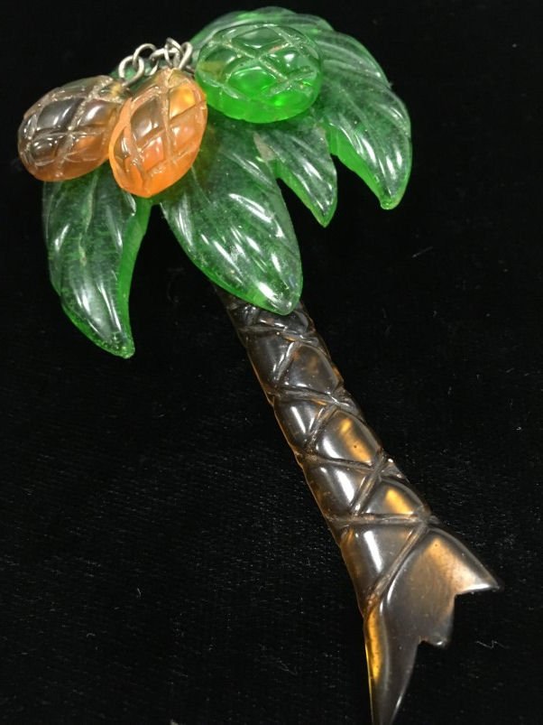1940s Apple Juice Lucite Palm Tree: Whimsical 1940s carved apple juice Lucite palm tree with 3 dangling coconuts, coconut connector is extended at back so it could be worn as a pendant, 3 3/4" long and 2 1/8" wide.