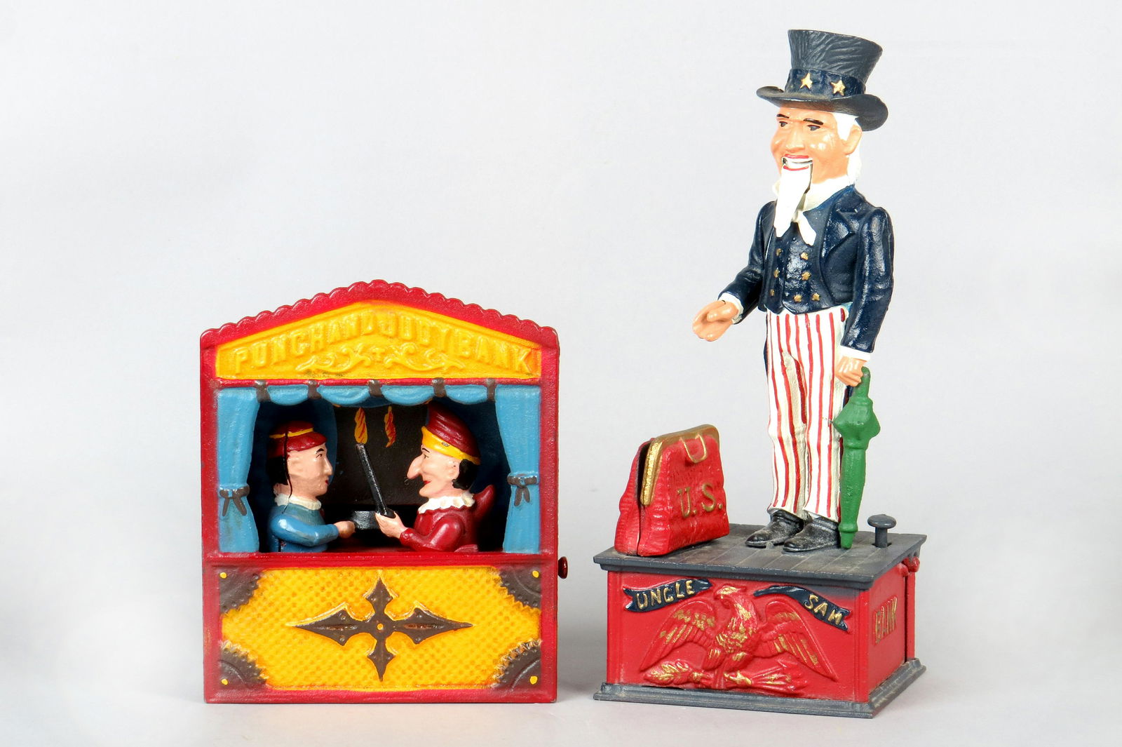 Lot of 2 Modern Mechanical Banks: 2 Modern Mech. Banks, CI: "Punch and Judy Bank", in OB, "John Wright"; "Uncle Sam Bank", Book of Knowledge