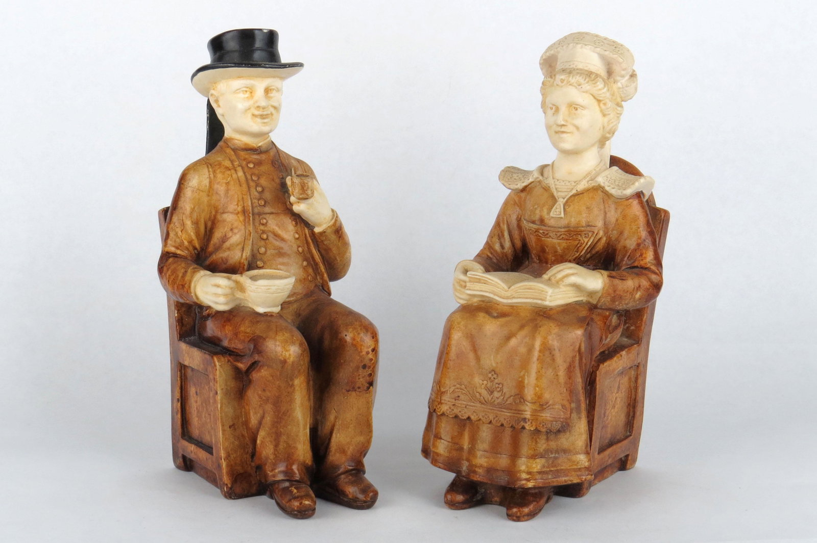Lot of 2 Figures in Chair Banks: 2 Figures in Chair Banks, Pottery: Seated Man w/Pipe and Coffee, Chip on Hat; Seated Woman w/Book