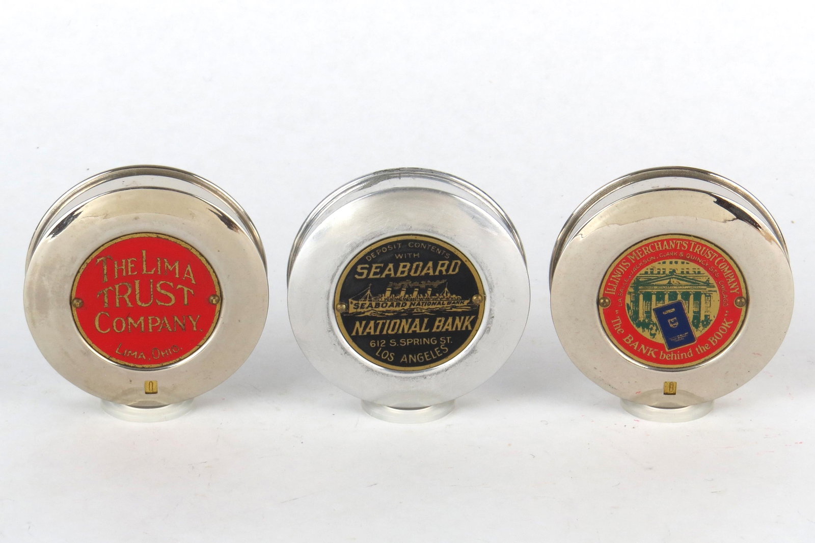 Lot of 3 Round Pocket Banks: 3 Round Pocket Banks, Silvered Metal: "The Lima Trust Company, Lima, Ohio"; "Seaboard National Bank, Los Angeles"; "Illinois Trust Company"