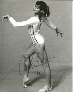 Nadia Comaneci signed 10x8 black and white photo. Romanian retired gymnast and a five-time Olympic: Nadia Comaneci signed 10x8 black and white photo. Romanian retired gymnast and a five-time Olympic gold medalist, all in individual events. In 1976 at the age of 14, Comaneci was the first gymnast to