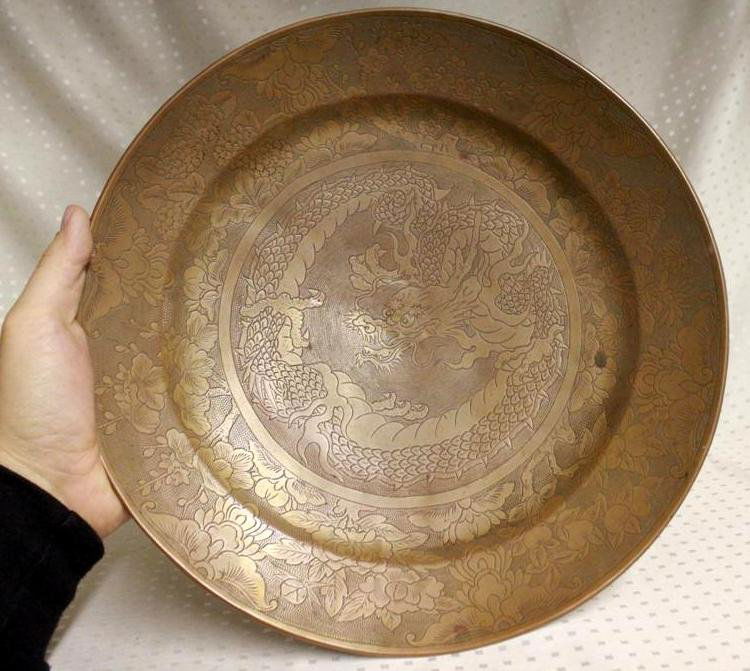 Large Antique Chinese Brass Engraved Dragon Bowl Charge: Beautiful late 19th Century early 20th Century Bowl/charger. Engraved with a large fierce dragon. With a outer decoration of Cherry Blossom trees, Chrysanthemums & other flowers. Unmarked. Very heavy