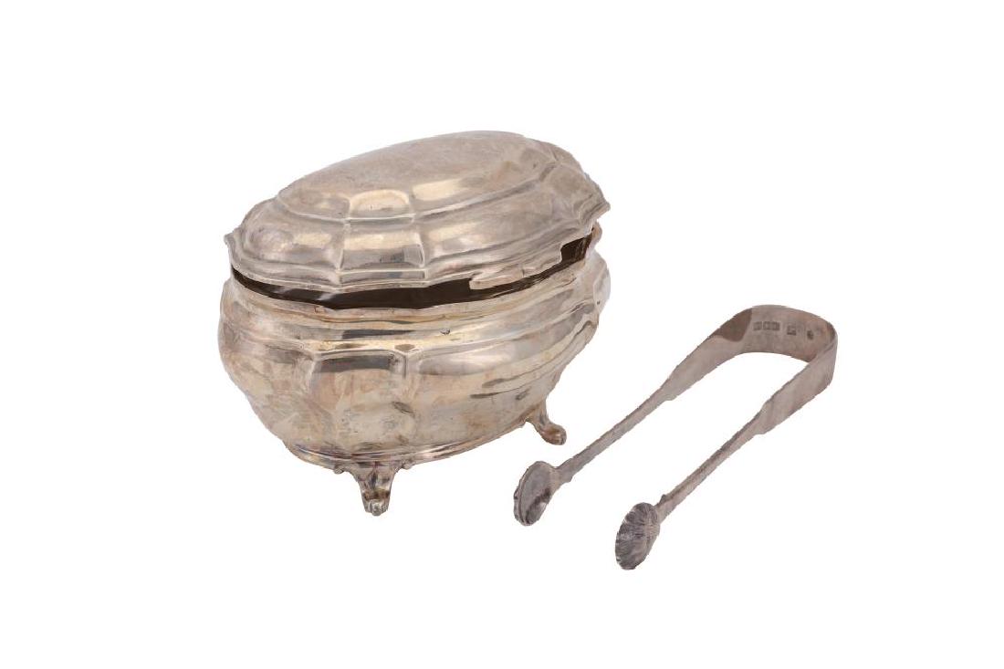 A Victorian sterling silver sugar box, London 1899 by: A Victorian sterling silver sugar box, London 1899 by Charles Stuart Harris int he 18th century German style, raised on four feet. Also to include a pair of George IV Scottish sugar tongs, with shell