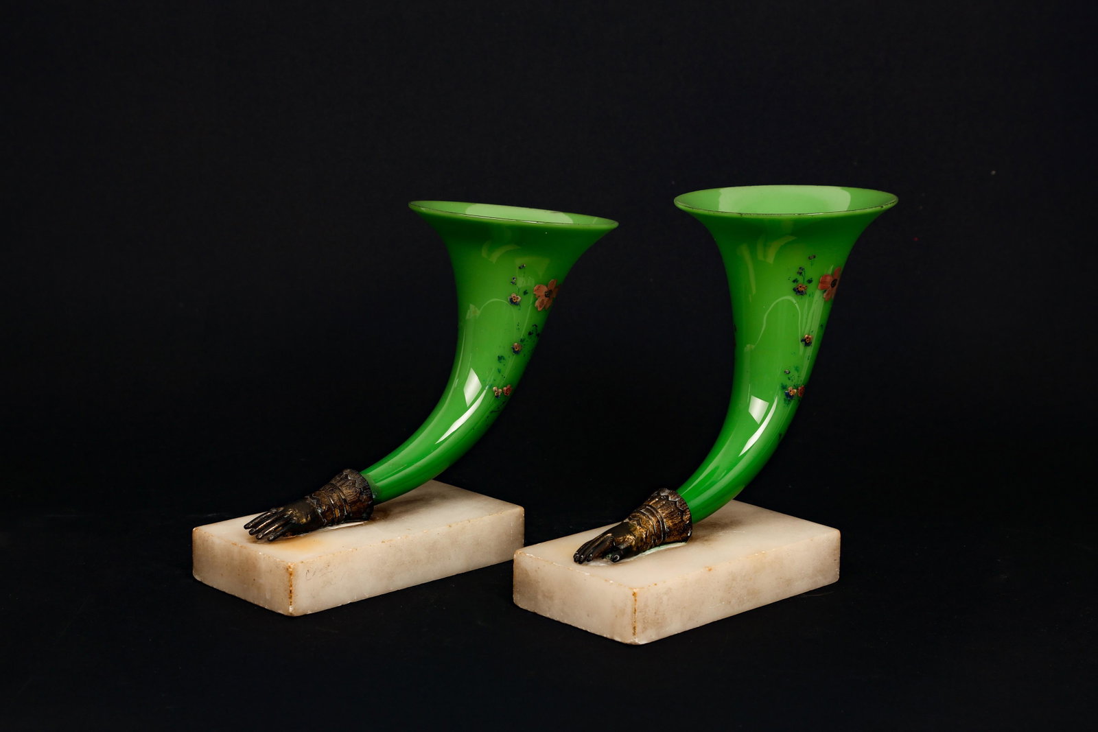 A PAIR OF 19TH CENTURY PAINTED GREEN GLASS, ORMOLU AND: A PAIR OF 19TH CENTURY PAINTED GREEN GLASS, ORMOLU AND MARBLE POSEY VASES the trumpet shaped vases painted with flowers, issuing from gilt bronze bases modelled as hands, on Carrara marble rectangular