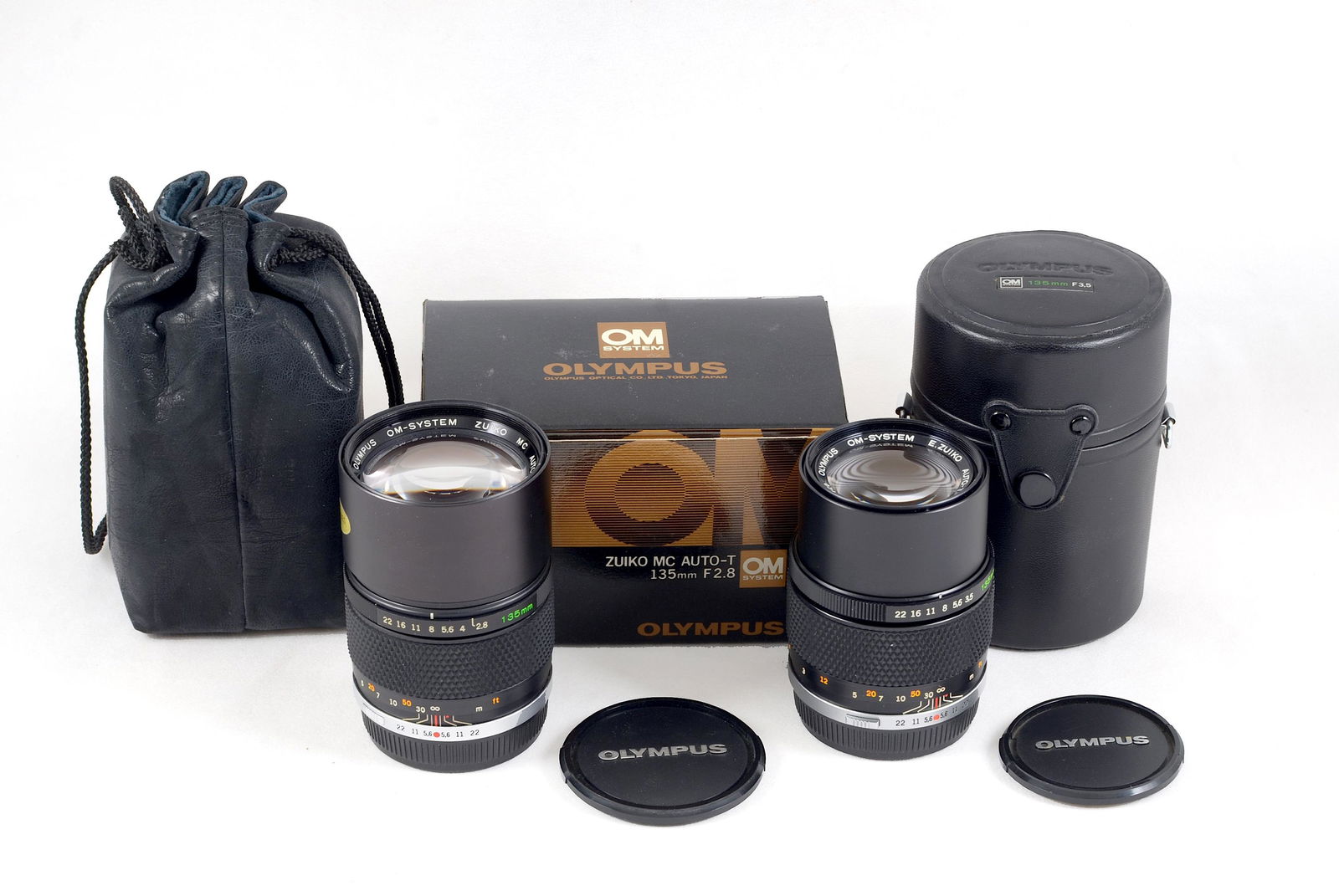 f2.8 & f3.5 Olympus OM Auto-T 135mm Lenses.: Comprising 135mm f2.8 #209312 with caps and in maker's box. Also 135mm f3.5 #349720 with caps and (scruffy) case. Each with minor internal dust and signs of light use. Provenance: The John Foster Olym