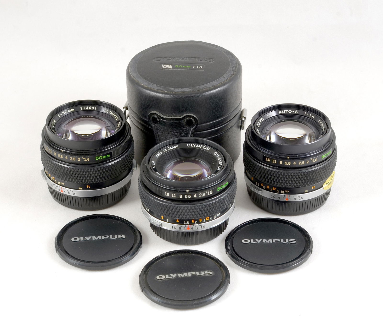 Olympus OM Auto-S 50mm f1.4 & f1.8 Lenses.: Comprising 50mm f1.4 #1007591 & #914681 with caps, and a 50mm f1.8 #3740554 with caps and case. All with slight internal fungus, signs of normal+ use . Provenance: The John Foster Olympus Collection