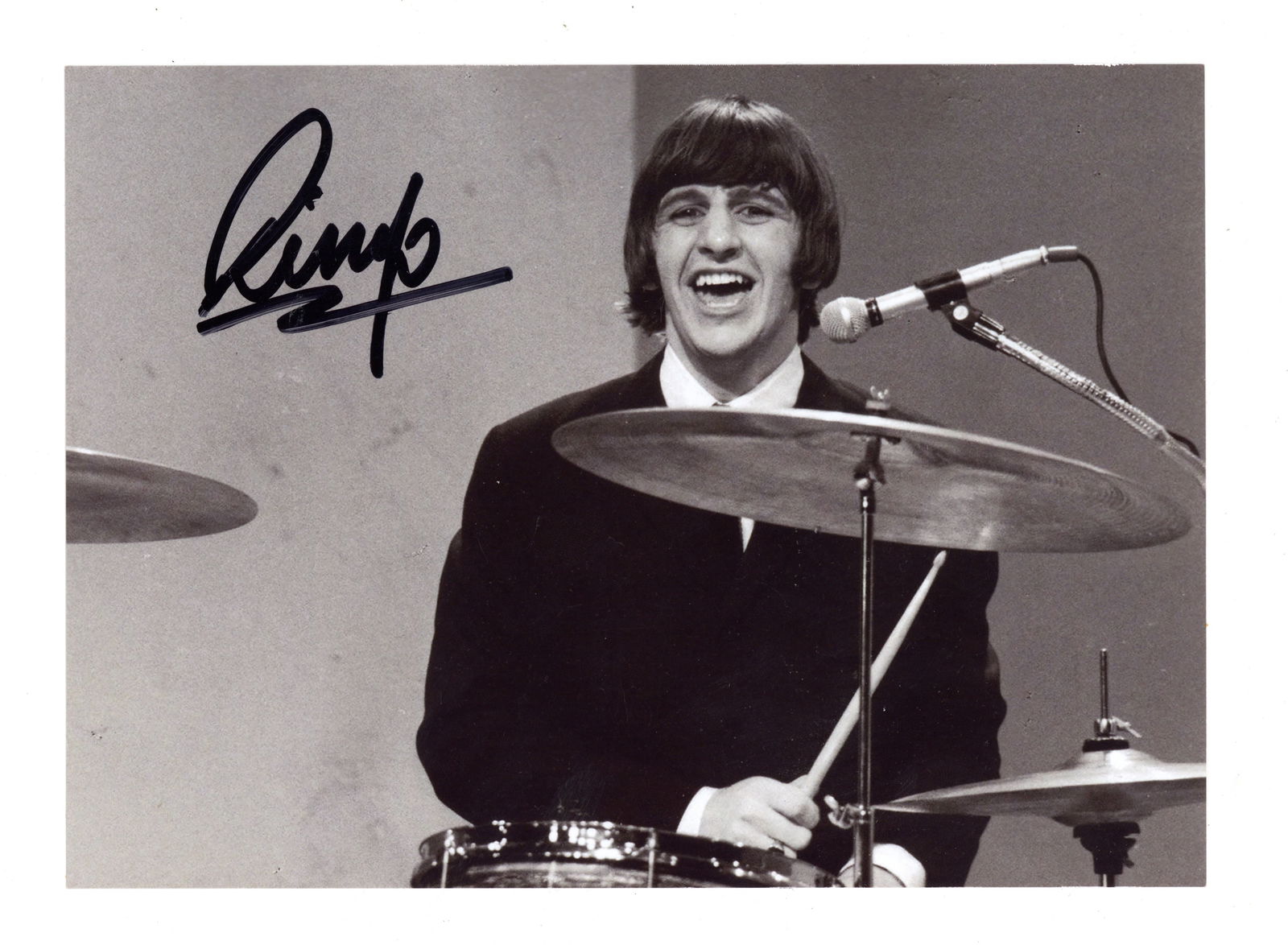Starr (Ringo): Starr (Ringo) Glossy black and white photograph of Ringo Starr playing the drums during a Beatles concert, signed in black felt tip near the top left corner, some tape remnants to the verso, 12.6 x 17