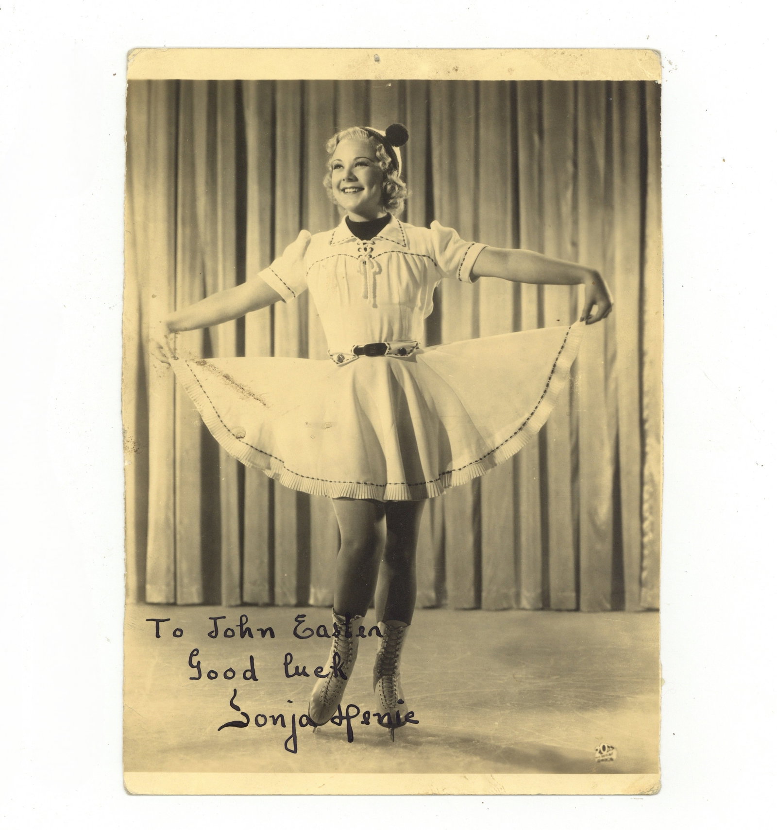 Henje (Sonja) Signed photograph: Henje (Sonja) Signed photograph Vintage full length photograph of Henje in her skating outfit, signed and inscribed "To John Easten, Good luck, Sonja Henje" in the lower portion of the image, some