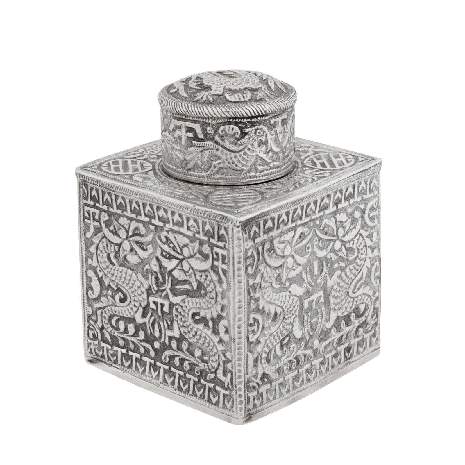 Kashmir circa 1910 An unusual early 20th century Anglo – Indian unmarked silver tea caddy: Of cuboidal form with a pull off cylindrical cap. Chased decoration of trailing Chinese dragons amidst stylised forms, also with stylised Shou character symbols. Height – 9.7 cm / 3.8 inches Weight