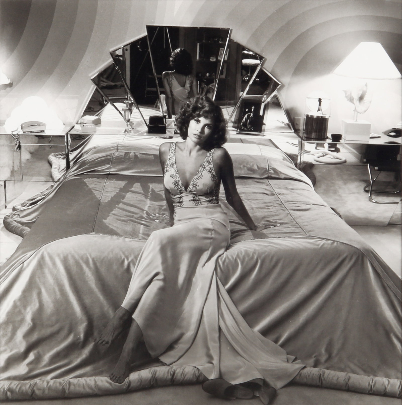 § Terry O'Neill (1938-2019) Raquel Welch at Home in Beverly Hills, 1976: Silver gelatin print, printed later, image size 21 x 21cm, sheet size 30.5 x 24cm, pasted down to board, signed by the photographer and editioned 2/150 in felt-tip pen on the overmount, with O'Neill's