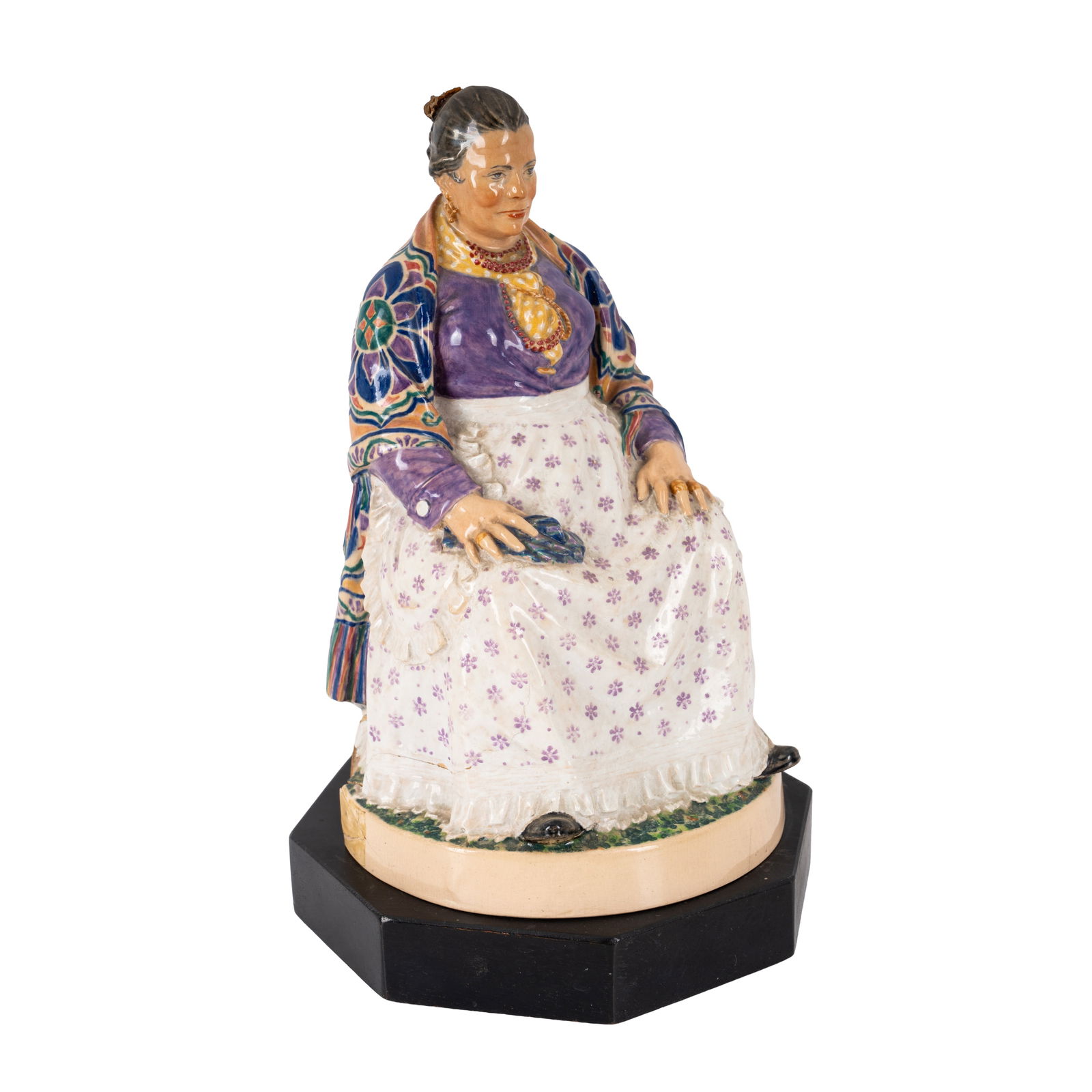 Charles Vyse (British 1882-1971) Model of a seated female lavender seller: Circa 1920 Painted and glazed earthenware, on wooden plinth Incised 'C VYSE CHELSEA' to the side of the circular foot 21cm high (23.5cm high including plinth)