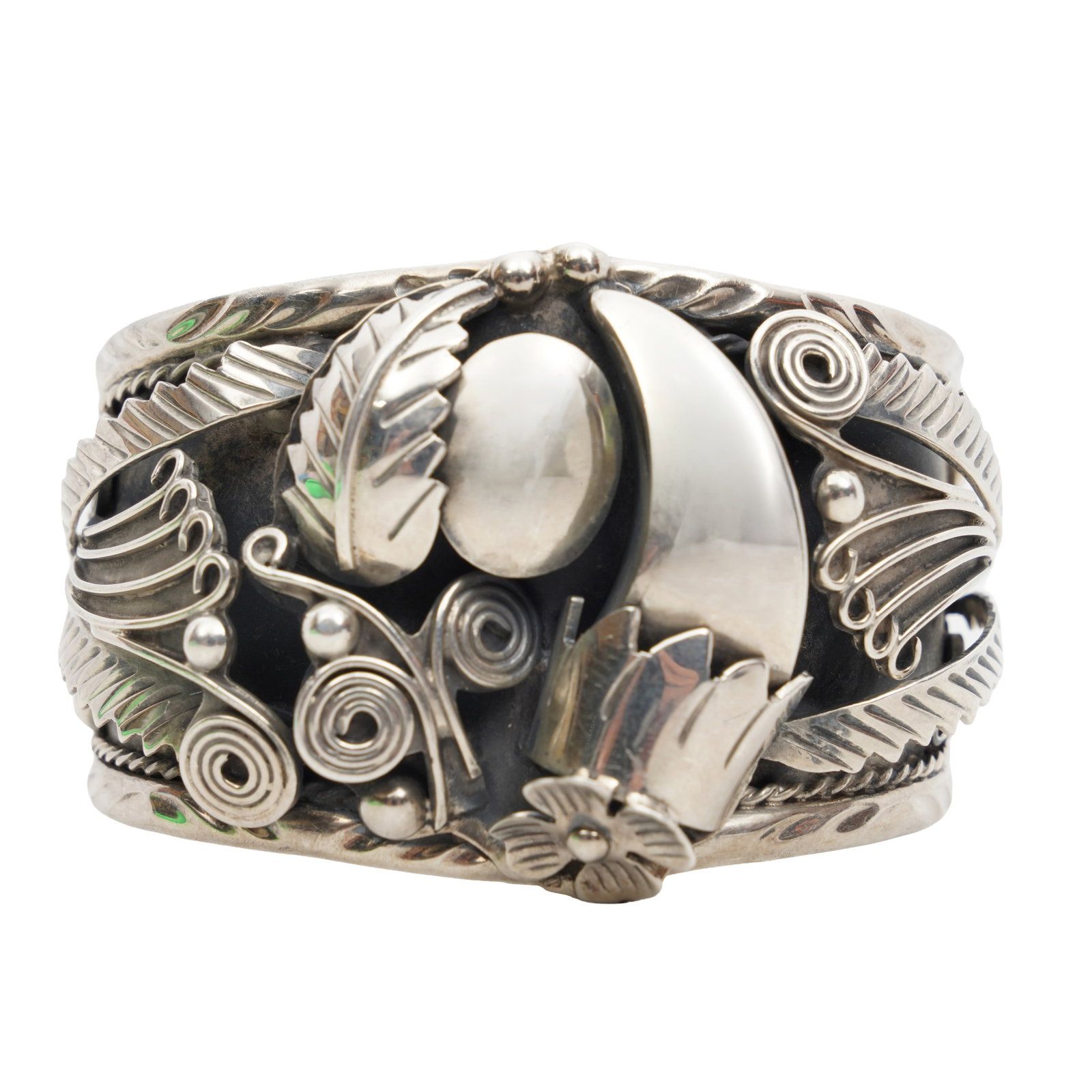 A bangle White metal: A bangle White metal Of tapered design, decorated with applied floral and foliate motifs, stamped Mexico 950; inner diameter 6.5cm