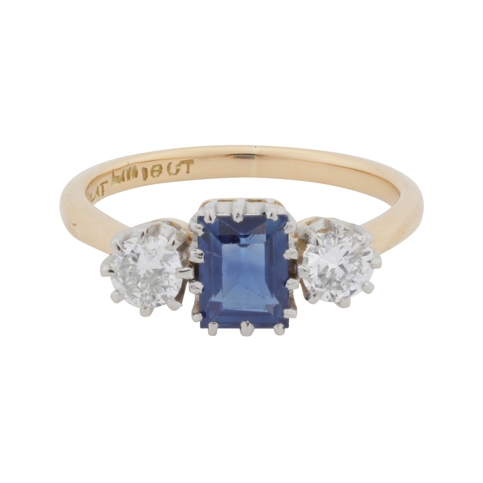 A sapphire and diamond three stone ring Yellow and white metal: A sapphire and diamond three stone ring Yellow and white metal Claw-set with a rectangular step-cut sapphire, flanked by brilliant-cut diamonds, to tapered shoulders, diamonds approx. 0.30 carat