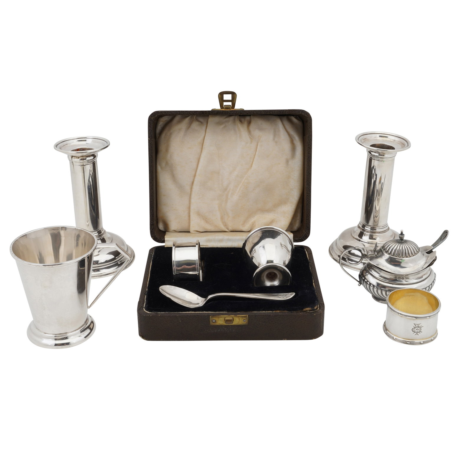A mixed group of sterling silver: A mixed group of sterling silver Comprising a pair of filled dwarf candlesticks engraved with crests, christening mug, mustard pot, napkin ring, egg cup and spoon. (Q) Weight – 200 grams / 6.43 