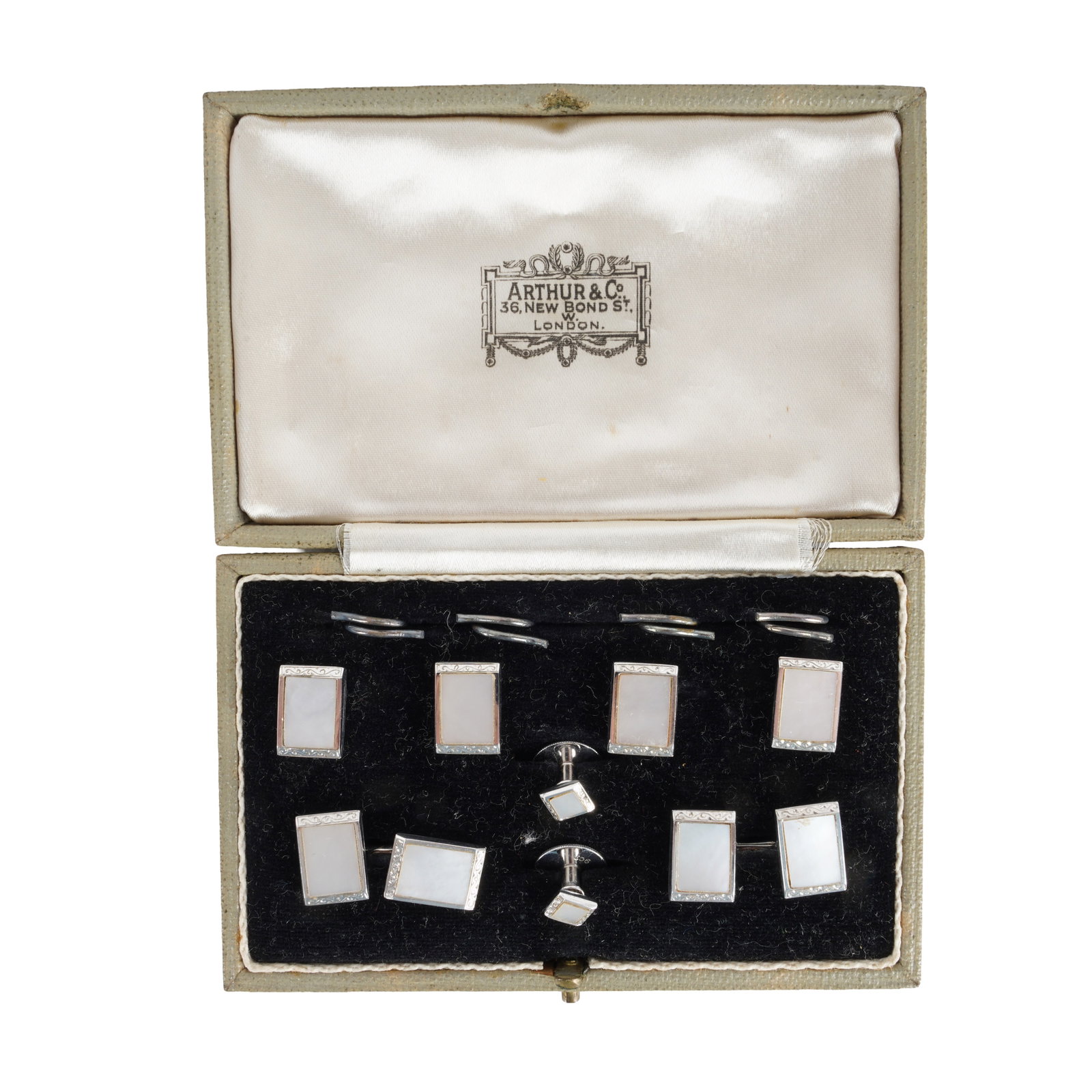 A mother of pearl dress set White metal: A mother of pearl dress set White metal Comprising: Four buttons, two dress studs, and a pair of double-sided cufflinks, each designed as a rectangular mother-of-pearl plaque within engraved borders,