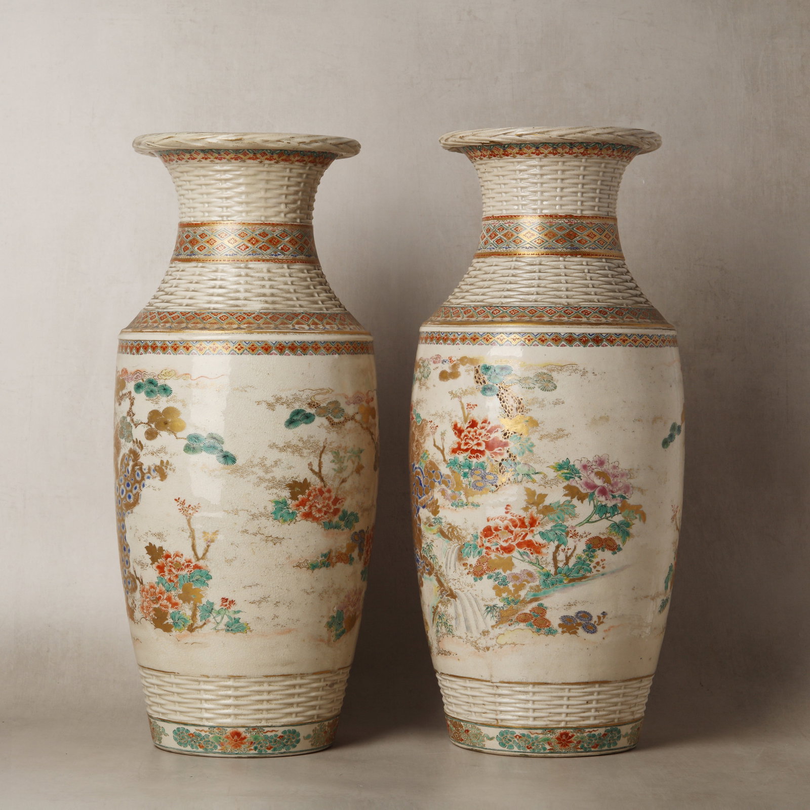 A pair of Japanese Satsuma 'basket weave' vases, Meiji period, 19th century: The finely potted vases of tall form with a curved neck and splayed rim, finely decorated with the satsuma palette to the exterior depicting large floral motifs including pine trees, peonies and chrys