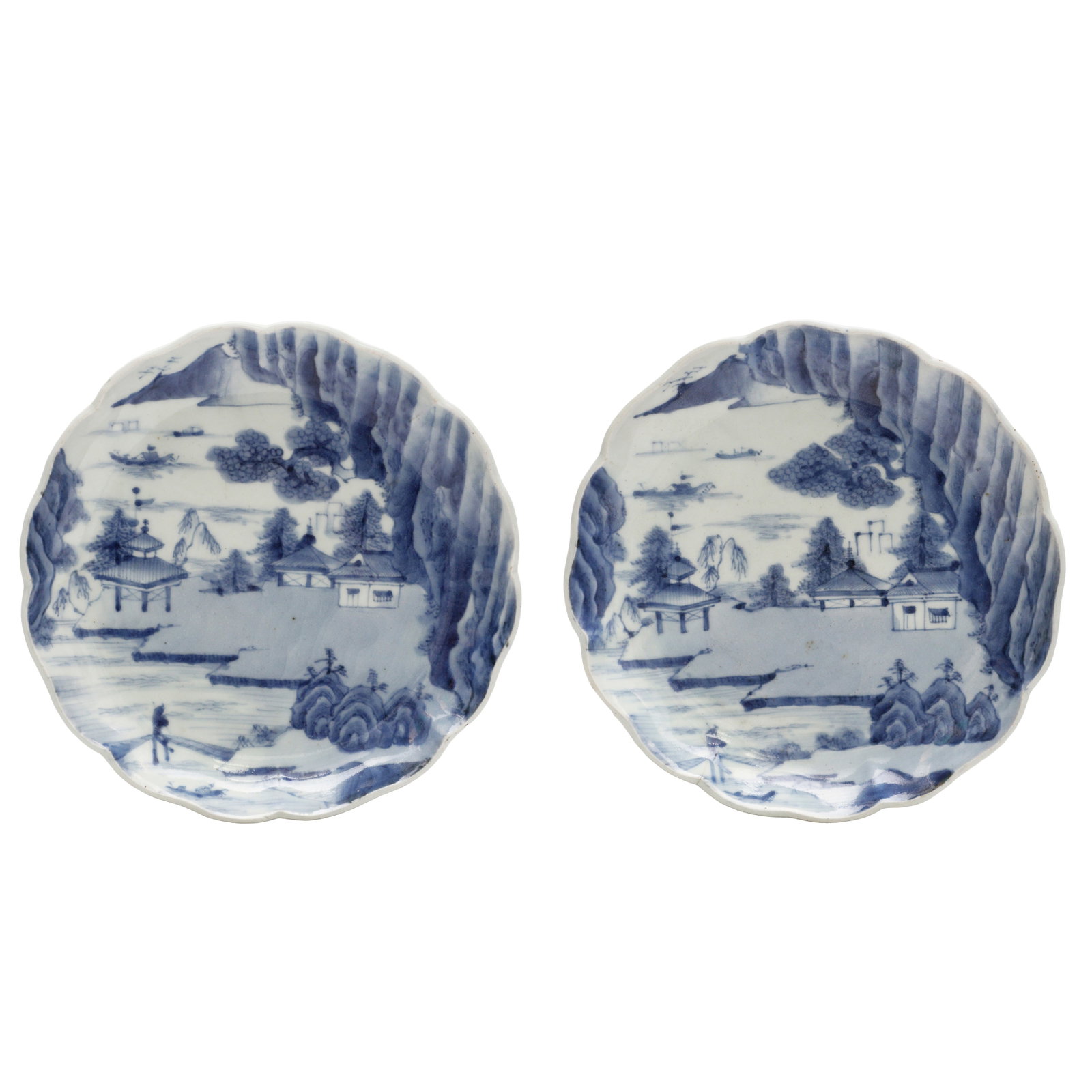 A pair of Japanese Arita blue and white 'landscape' dishes, Edo period: Each foliate dish painted to the interior with a coastal landscape scene dotted with boats, dwellings and foliage, the base with a four-character Fugui Changchun mark in underglaze-blue Size:(20.7cm d