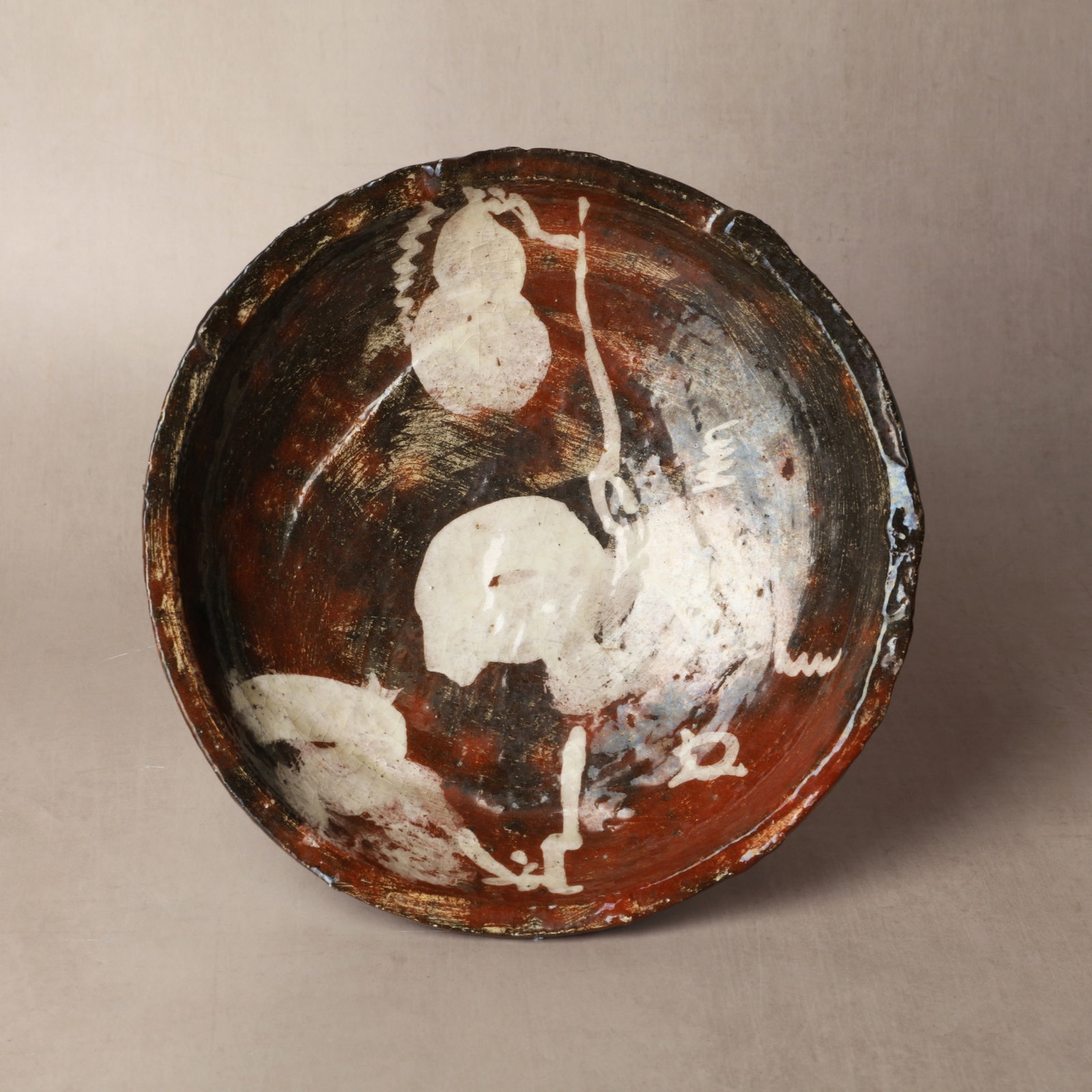 Otani Sonyu (Japanese, 1886?1939): A robustly potted chawan tea bowl, Gentaku ware sculputed by hand, of shallow form with a deliberately uneven rim, covered overall in an iron rich glaze further adorned with white-slip, the small foot
