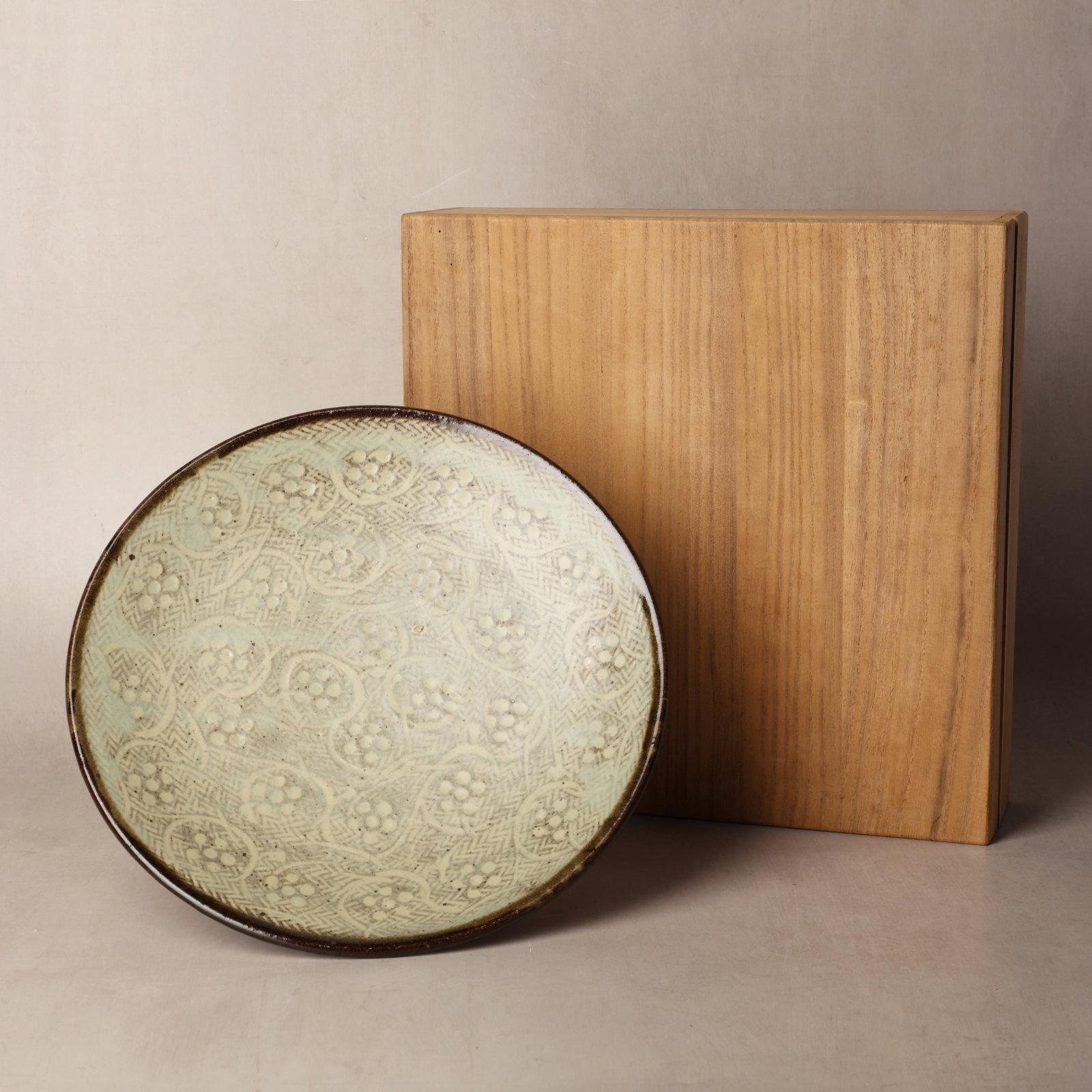 Shimaoka Tatsuzo (Japanese, 1919?2007): The robustly potted dish of shallow form, the interior decorated in the artists jomon zogan signature rope-impressed technique, together with plum-blossom roundels, the glaze in greyish-white tones, t