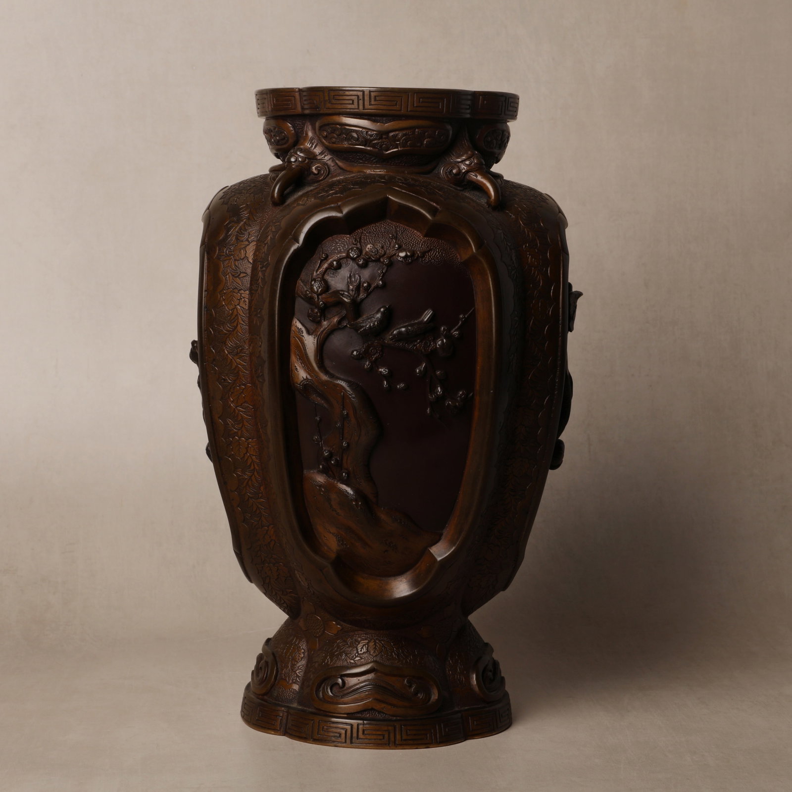 A Japanese bronze 'birds and floral? vase, Meiji period: The robustly cast and heavy bronze vase of ovoid form, decorated to the exterior with four panels of birds and foliage, further adorned with stylised floral scrolls finely incised onto the body, the b