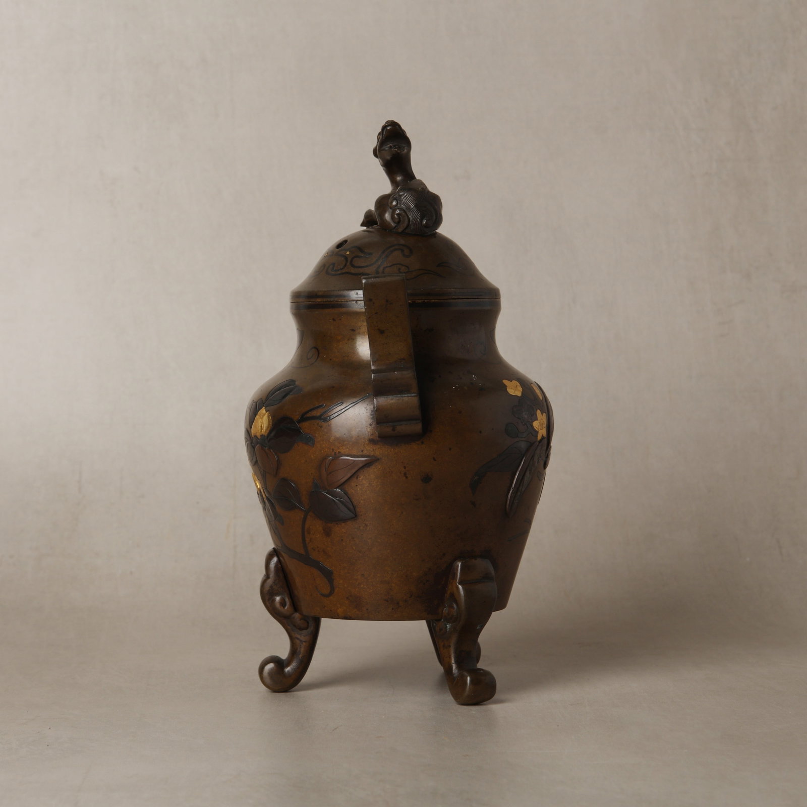 A Japanese bronze and mixed metal 'floral' koro incense burner and cover, Meiji period, 19th century: The bronze and mixed metal cast incense burner and cover, decorated to the exterior with flowering prunus branch motifs and other stylised motifs including clouds, the feet formed as scrolls, the top 