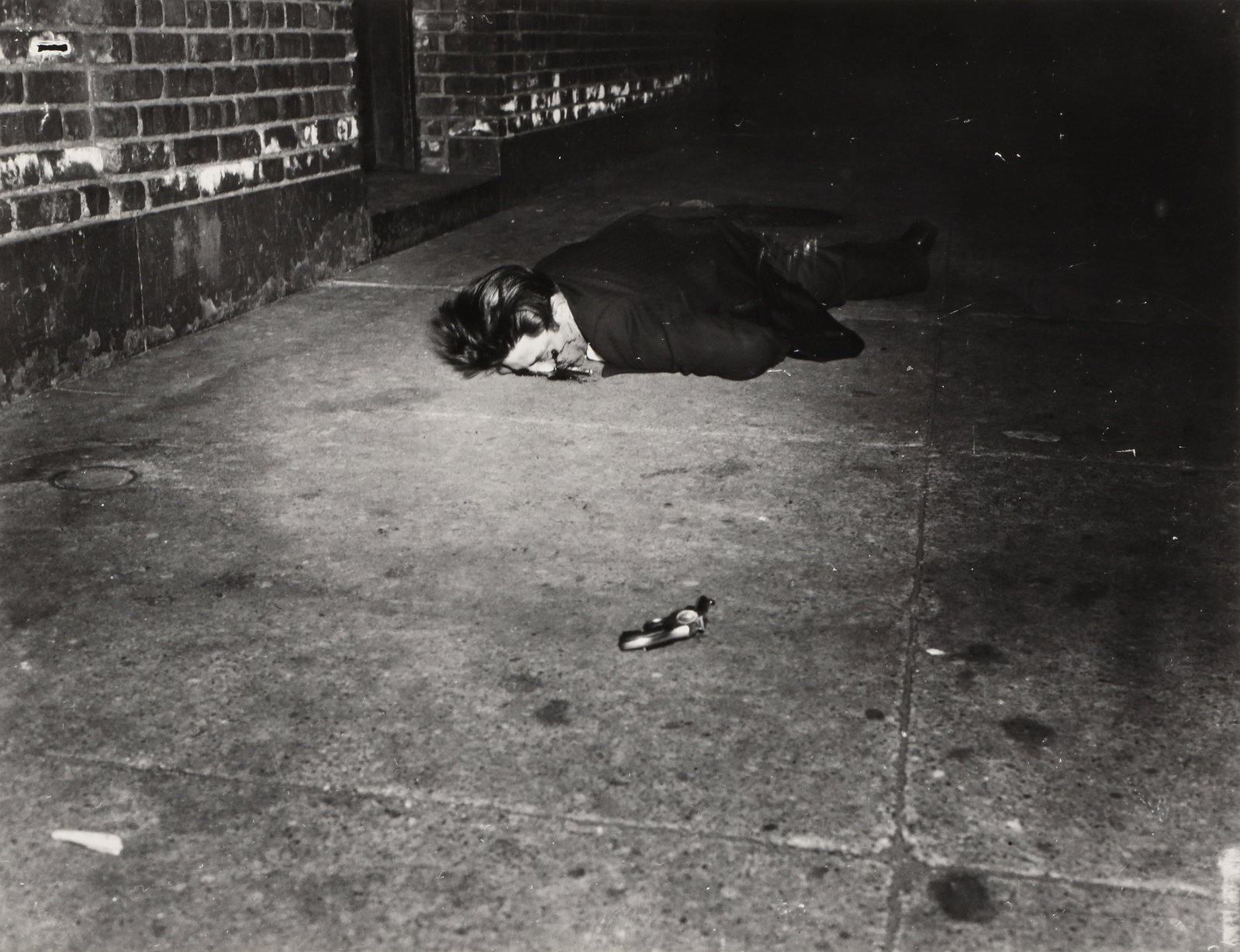 Weegee [Arthur Fellig] (1899-1968) Crime Scenes [Corpse with Revolver, 1942 and Victims, c.1940]: A pair of silver gelatin prints, printed 1980s by Sid Kaplan, image sizes 32 x 41.8cm and 32 x 41cm, sheet sizes 40.7 x 48.5cm and 40.7 x 49cm, with 'Weegee The Famous' and Kaplan's credit stamps vers