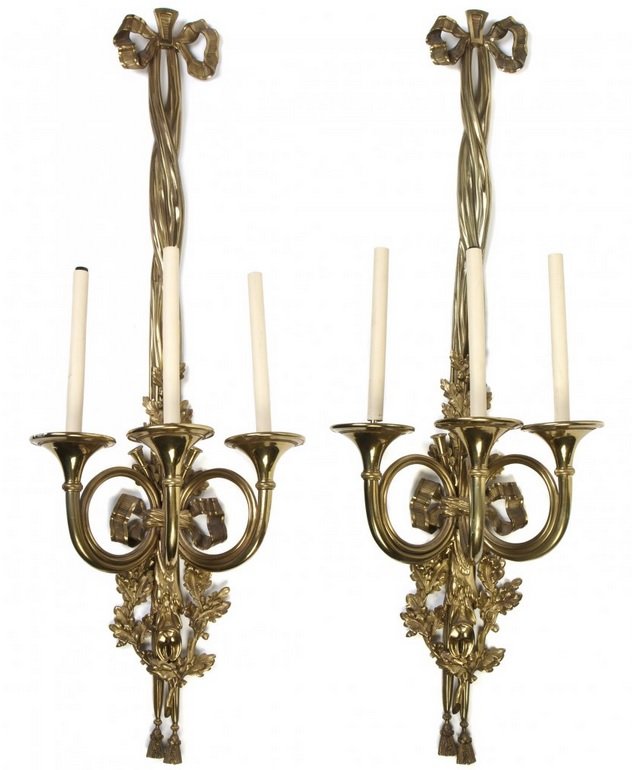 A Pair of Gilt Bronze Three-Light Sconces: A Pair of Gilt Bronze Three-Light Sconces, each having a ribbon-tied backplate cast in a hunt motif with oak leaves, acorns and game, with candle arms in the form of horns. Height 44 1/8 inches. NO IN