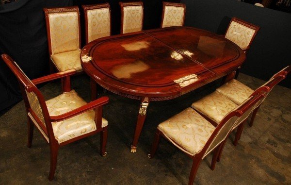 Versace Dining Table and Nine Chairs: Classic Versace design laquered wooden dining table with nine matching chairs. Cream colored upholstery on chairs with goldleaf accents. Glass top. Includes 22" leaf. 32" x 107" x 46.5". NO INTERNATIO
